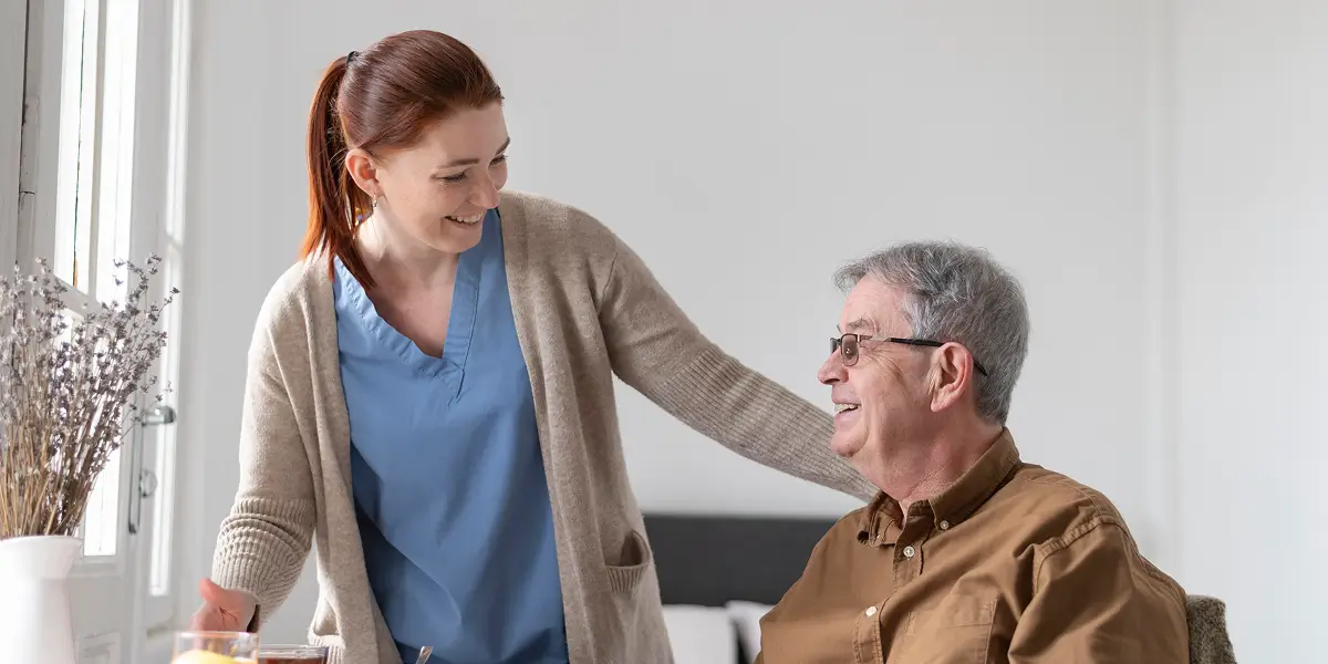 Caregiver and senior holding hands and smiling